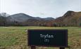 Field name sign with mountains and camping field behind