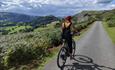 A cyclist enjoying the scenery whilst riding along a quite country lane within the Dee Valley