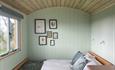 Inside the Elderflower shepherd hut, you can see the double bed, pictures on wall and corner of kitchen area.