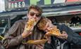 Two festival visitors are eating loaded hot dogs.