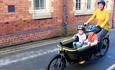 A mother and two young children using an e-cargo bike to explore Llangollen town centre