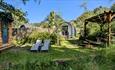 View of the Orme glamping pod gardens with outdoor undercover seating and a Finnish Sauna