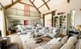 Barn lounge with laura ashlet sofas. Cream bookcases and oak beams. Pink doors. Ysgubor Degwm