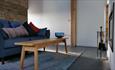 The living room with large double-sided woodburning fireplace, slate floor, white and timber walls inside the glamping barn