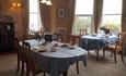 Dining room with three separate tables and two large windows.