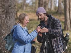 Man teaching woman how to use her DSL camera.