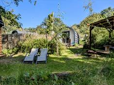 View of the Orme glamping pod gardens with outdoor undercover seating and a Finnish Sauna