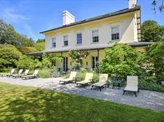 Plas Bodegroes outside shot of the house with sun loungers outside.