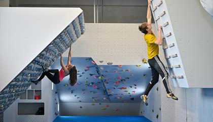 Strong teenage girl and boy climb on short overhanging walls in the training area