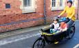 A mother and two young children using an e-cargo bike to explore Llangollen town centre