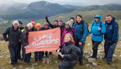 A group of walkers on Snowdon holding a Large Outdoors flag