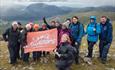 A group of walkers on Snowdon holding a Large Outdoors flag
