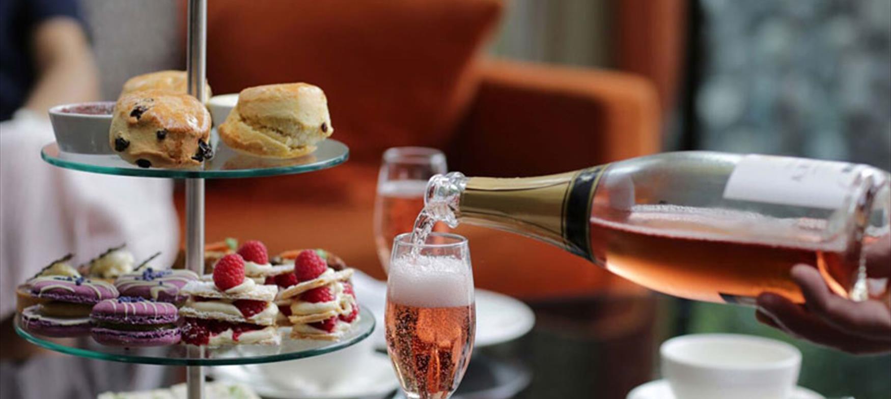 Champagne being poured, with scones and cakes in the background