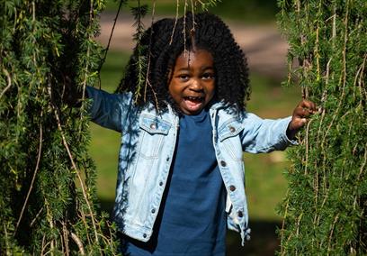 Young girl peeping through tree branches