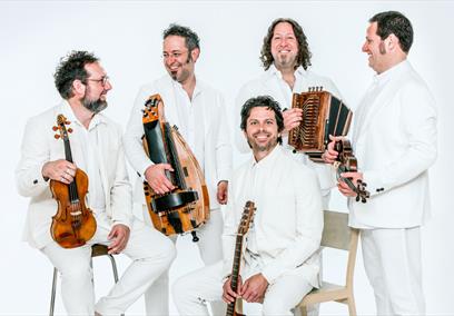 An image of five men in white suits holding instruments