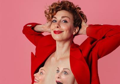 Helen Duff wearing a red blazer stood in front of a pink background