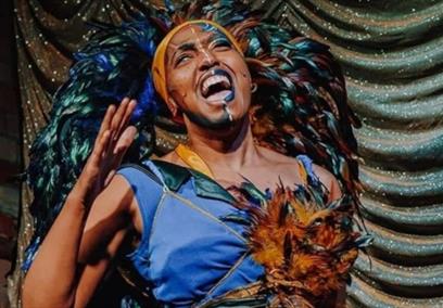 A performer wearing a blue dress and feathers