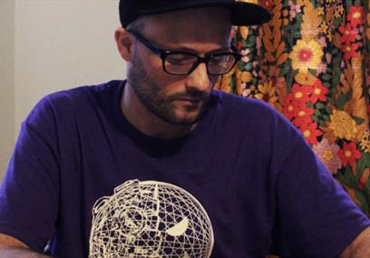 A man wearing a purple shirt with a white globe on the front