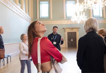 A guided tour group in the Ball Room at Bath Assembly Rooms