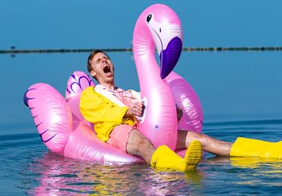 Harry baker sitting on a inflatable pool flamingo.