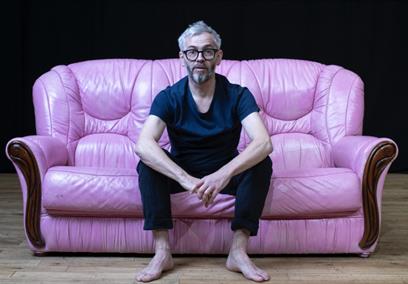 A man sat on a pink leather sofa
