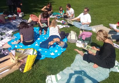A group of people sitting on a field on picnic blankets