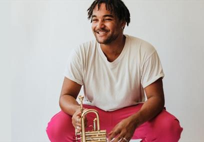 A man smiling while sitting holding a trumpet