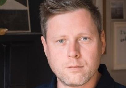 A headshot of a man looking directly at the camera