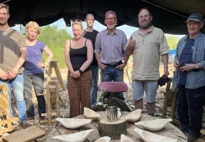 Group of people stood with their wooden carved bowls