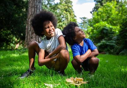 Two young boys crouching on woodland grass