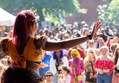 A women wearing a yellow top performing on a stage infront of a large crowd