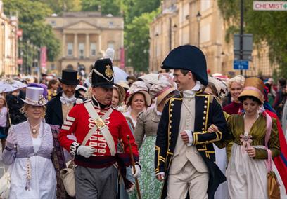 Two men and two women all dressed in Jane Austen-themed costumes leading a procession
