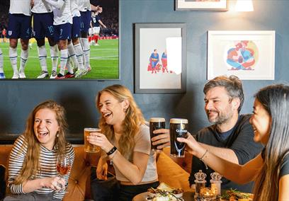 A group of people enjoying a pint watching the football