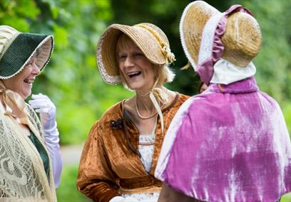 Three women dressed in Jane Austen attire.