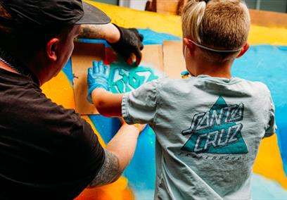 A young child and an adult partaking in a graffiti workshop