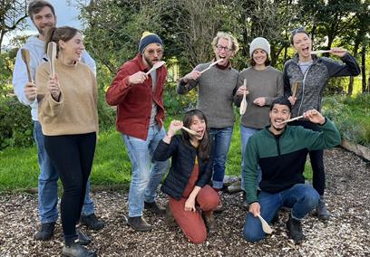 A group of people in woodland area with wooden spatulas