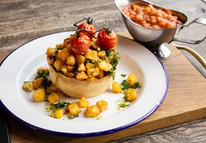 A breakfast pie topped with potatoes and vine tomatos