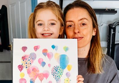 An adult and a child holding up a hot air balloon print