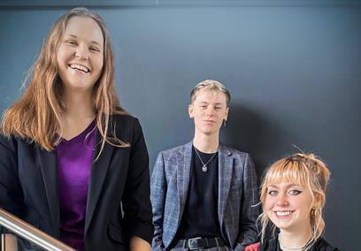Three people smiling while standing on a staircase