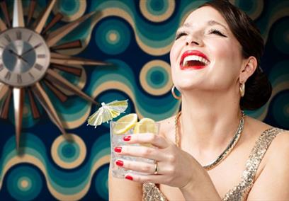 Woman with cocktail throwing her head back and laughing