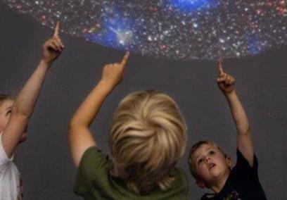 Three children pointing up at a planetarium display