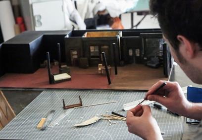 A man whittling wood at a table