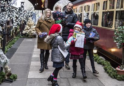 Family dresses up for Christmas next to a steam train