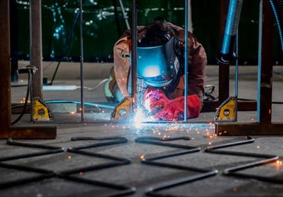 A performer dressed as a welder, welding metal on a stage