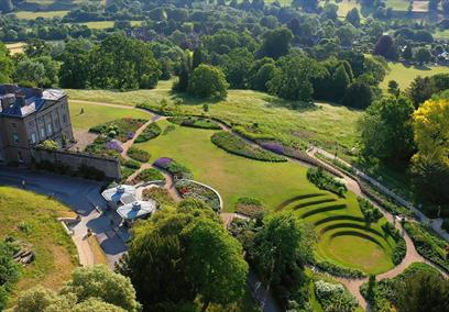 Manor house surrounded by green gardens overlooking valley