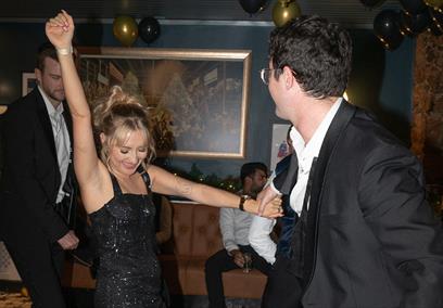 The image shows a lively and fun moment during a Racks Bar & Kitchen New Year's Eve celebration in Bristol. In the foreground, a young woman in a spar