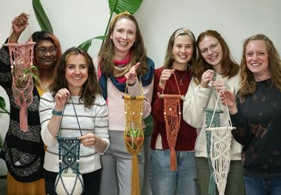 A group of women holding macrame plant hangers