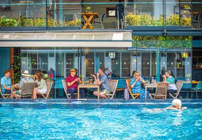 Bristol Lido - person swimming in pool and people dining by restaurant