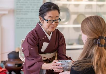 A woman holding a bowl in front of another woman