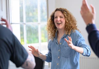 A women wearing a blue denim shirt taking part in an improv class